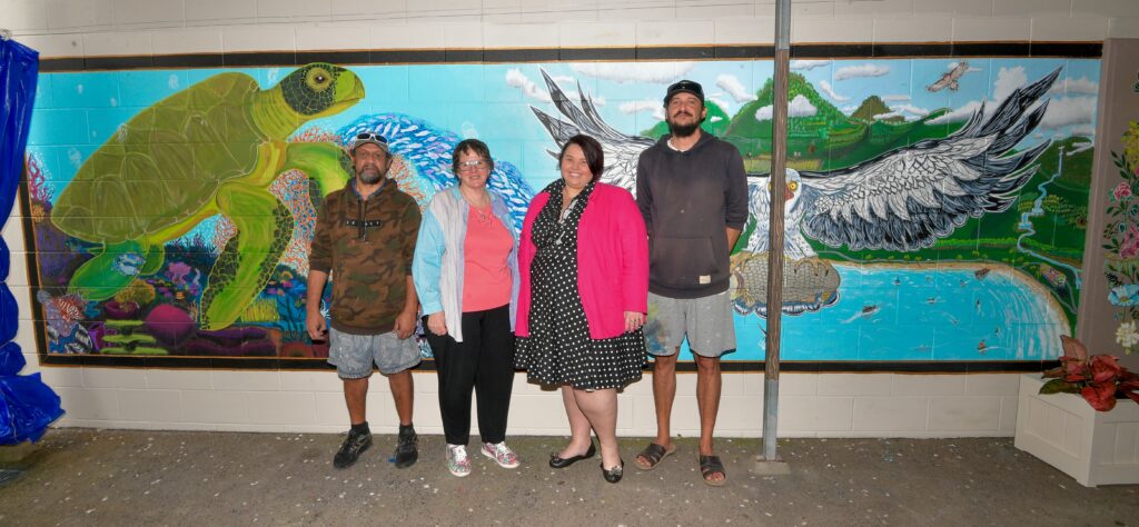 Michael Barba (Skills for Education and Employment SEE participant), Frances Mintron (SEE Trainer), Cassie Stanley (Executive Manager – Education and Training), and Warwick Spanner (SEE participant) in front of mural.