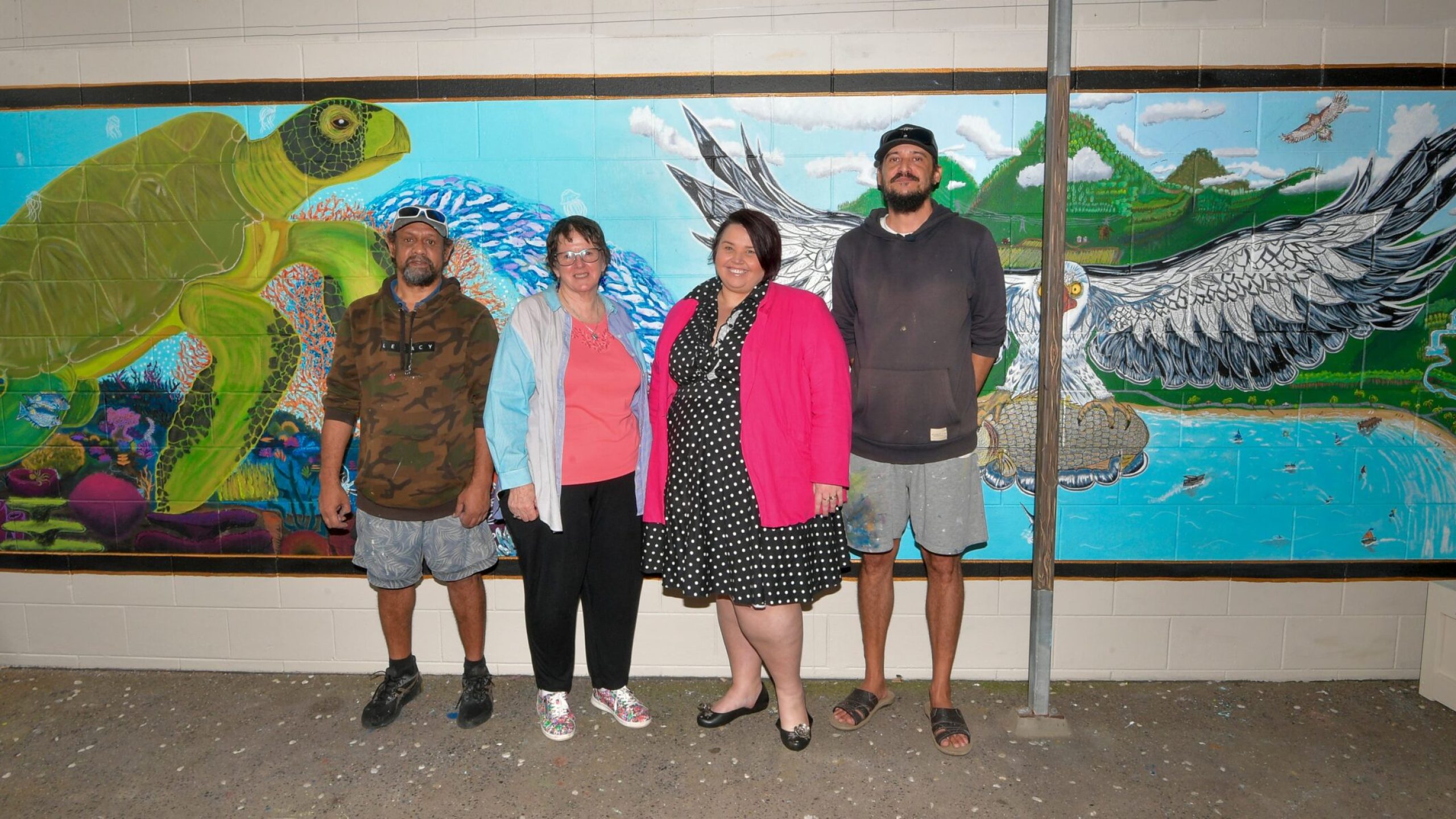 Michael Barba (Skills for Education and Employment SEE participant), Frances Mintron (SEE Trainer), Cassie Stanley (Executive Manager – Education and Training), and Warwick Spanner (SEE participant) in front of mural.