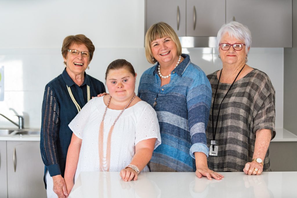 four women standing in a kitchen